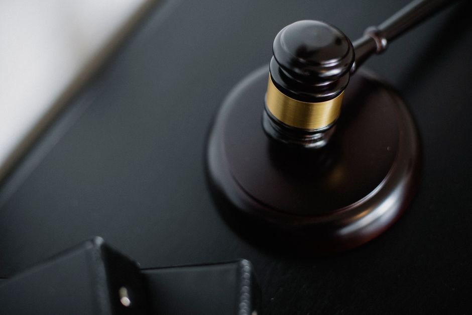 A wooden judge's gavel resting on a desk under low light, a conceptual image for courtroom drama movies
