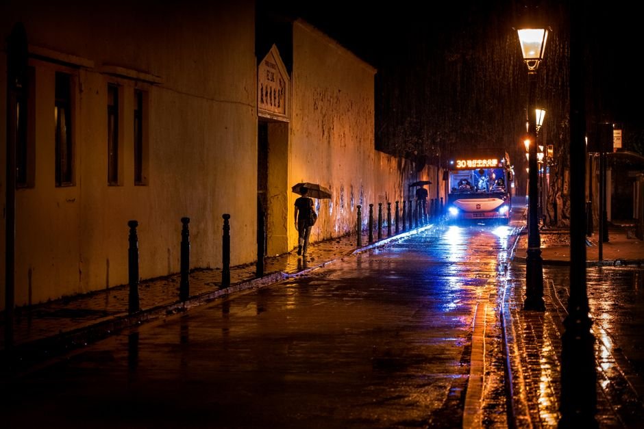 A car parked under a flickering neon sign on an empty wet street at night, a conceptual image for the best neo noir movies